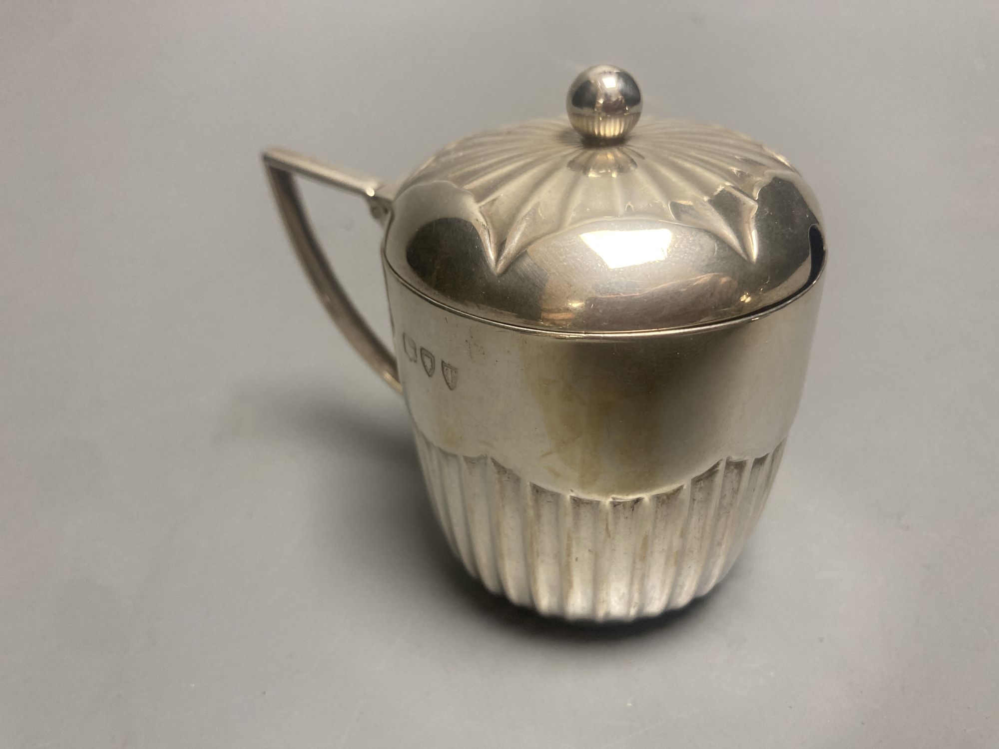 A late Victorian demi fluted silver mustard pot, London, 1894 and four other assorted later silver mustards.